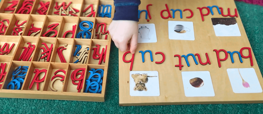 child spelling with movable alphabet and photo cards depicting words from the Montessori pink series